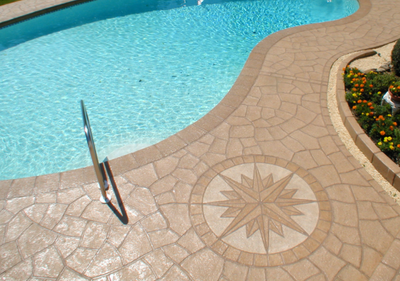 Decorative concrete pool deck with stamped in compass detail design.