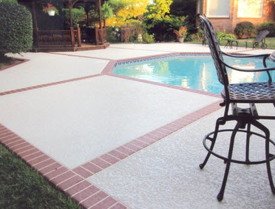 Textured gray concrete pool deck with brick stamped edging.