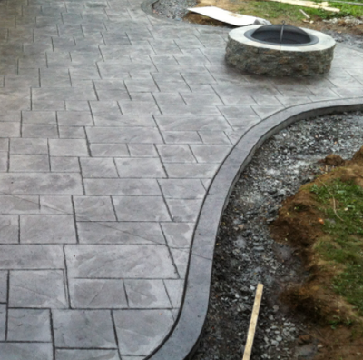 Gray stained stamped concrete patio with built in fire pit.